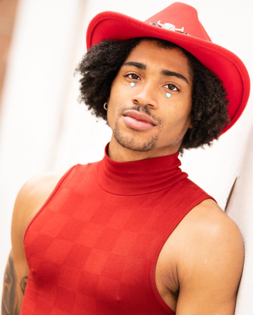Image of Preston Crowder wearing a red tanktop and cowboy hat looking into the camera.